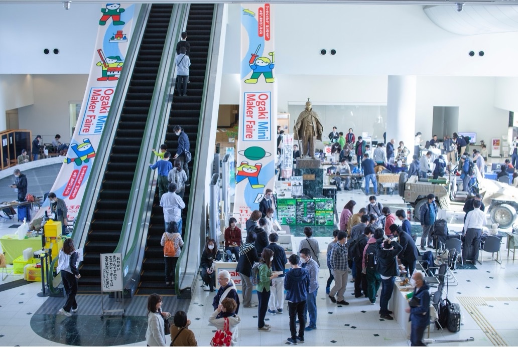 Ogaki Mini Maker Faire の会場。ソフトピアジャパン・センタービルのアトリウムで、エスカレーターに掲げた横断幕のまわりを来場者が歩いている